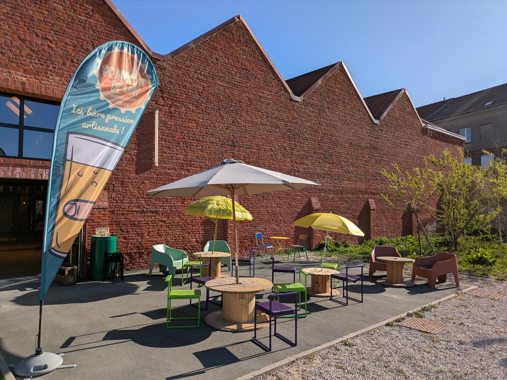 Terrasse de la Brasserie de Mai, façade en briques et parasols
